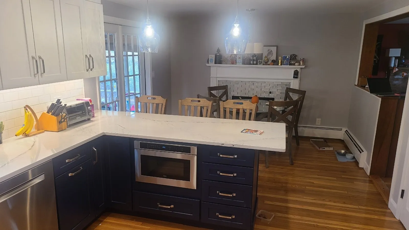 Open kitchen with navy base cabinets and quartz peninsula