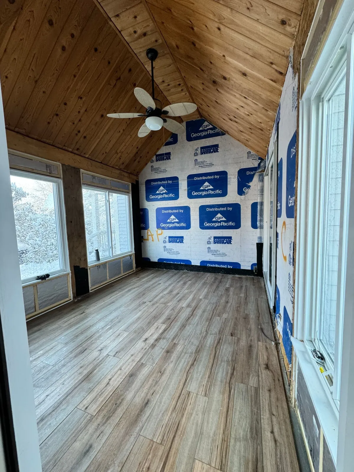 An empty room with a ceiling fan and a lot of windows