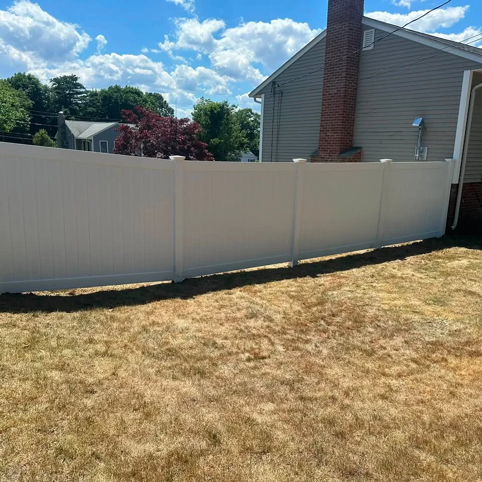 White vinyl privacy fence run in a back yard