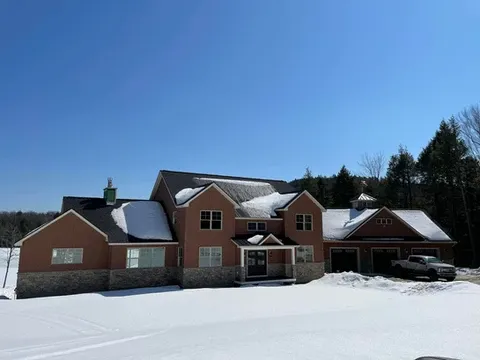 Large reddish-brown house with snow