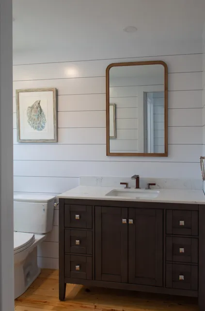 Bath with shiplap wall and dark vanity