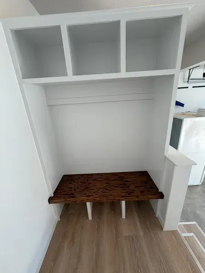The final, polished result of our recent custom mudroom built-in project, featuring white storage cubbies and a beautifully stained wood bench.