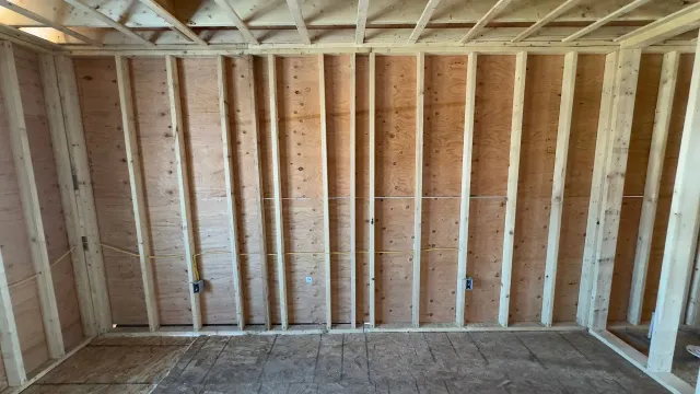 Interior of a room under construction with exposed wooden studs and framing.