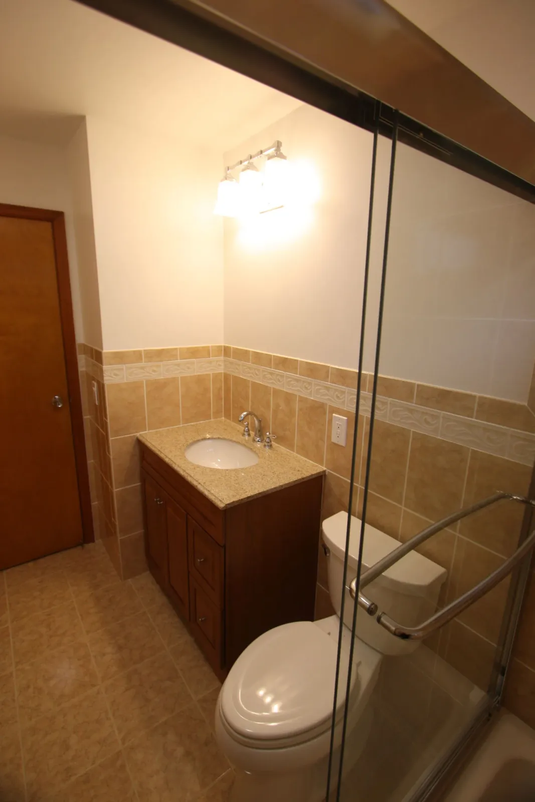 A bathroom with a toilet, a sink, and a sliding glass door.