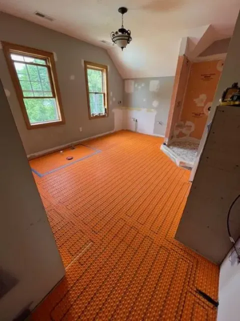 Dreamstate Renovations, LLC - Radiant heated floor installation with orange mesh underlayment in a room, showcasing the process of creating a cozy and energy-efficient living space.