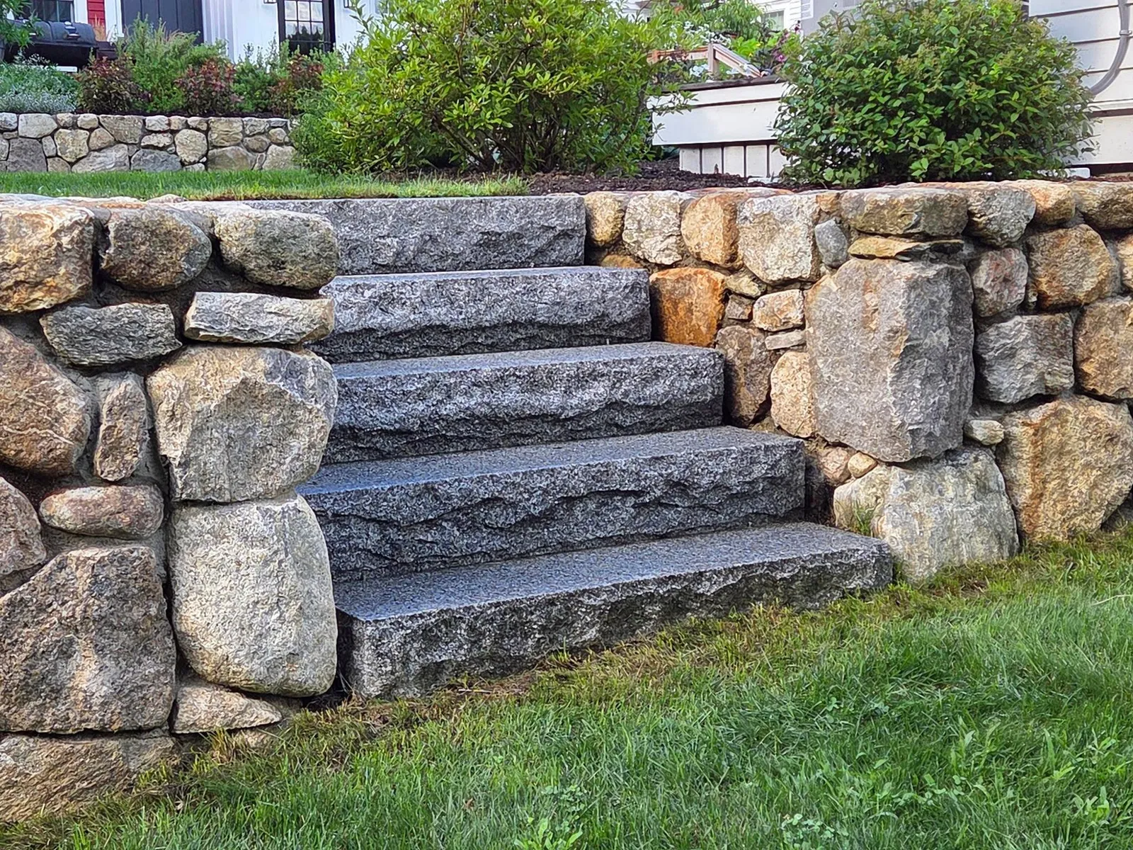 Natural stone just always feels so timeless!  We love this detail from a recent project. These granite steps, quarried locally and framed by a hand-built fieldstone wall, create a welcoming transition while blending seamlessly into the landscape. It's the kind of detail that looks like it's always belonged there.

 #LandscapeArchitecture #GraniteSteps #FieldstoneWall #NaturalStone #Stonework #AngieVergeLandscapeDesign