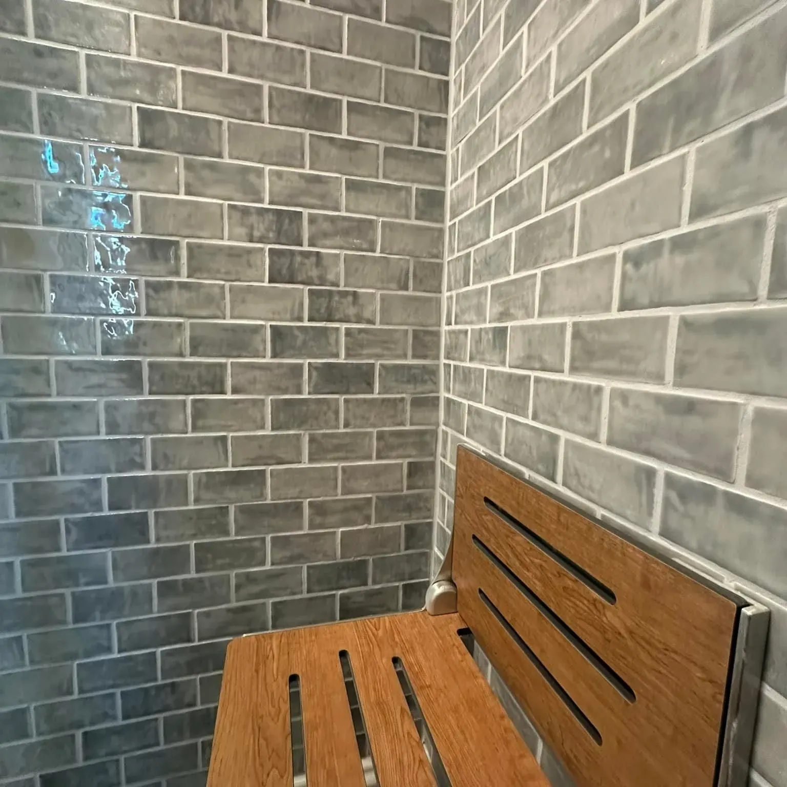 There is a wooden bench in the corner of the shower.