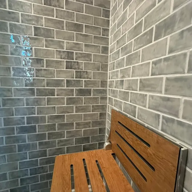 There is a wooden bench in the corner of the shower.