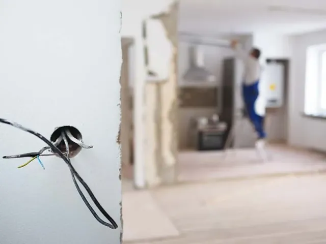 A person is standing in a room with a hole in the wall.