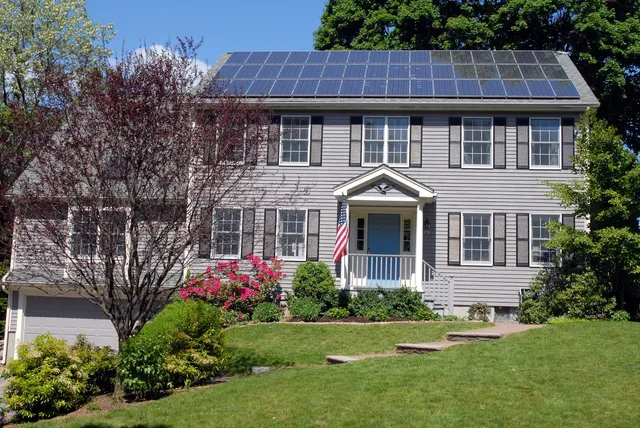 Suburban house with a full rooftop solar array on the main roof plane.