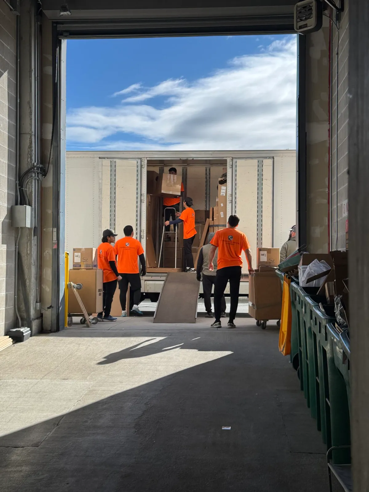 Commercial movers loading equipment into truck at warehouse