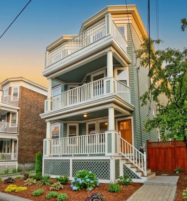 Three-story residential building at 17 Smith Place with green siding, white trim, and multiple balconies, surrounded by landscaping and a paved driveway.