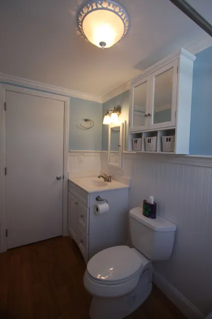 A bathroom with a toilet, sink, and mirror.
