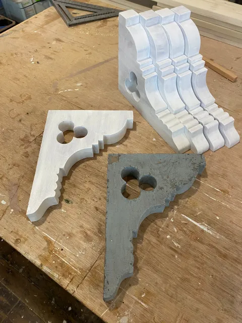 Woodwork pieces with intricate carvings and cutouts on a woodworking table.