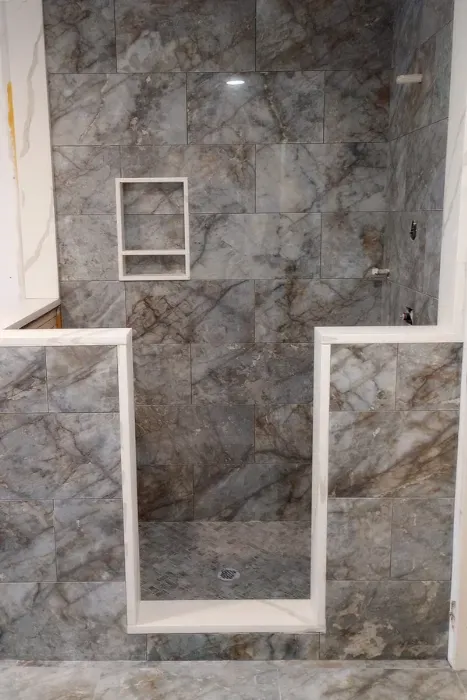 Large-format gray marble-look tile shower surround with niche and curb by Link Services Pro in Shrewsbury, MA