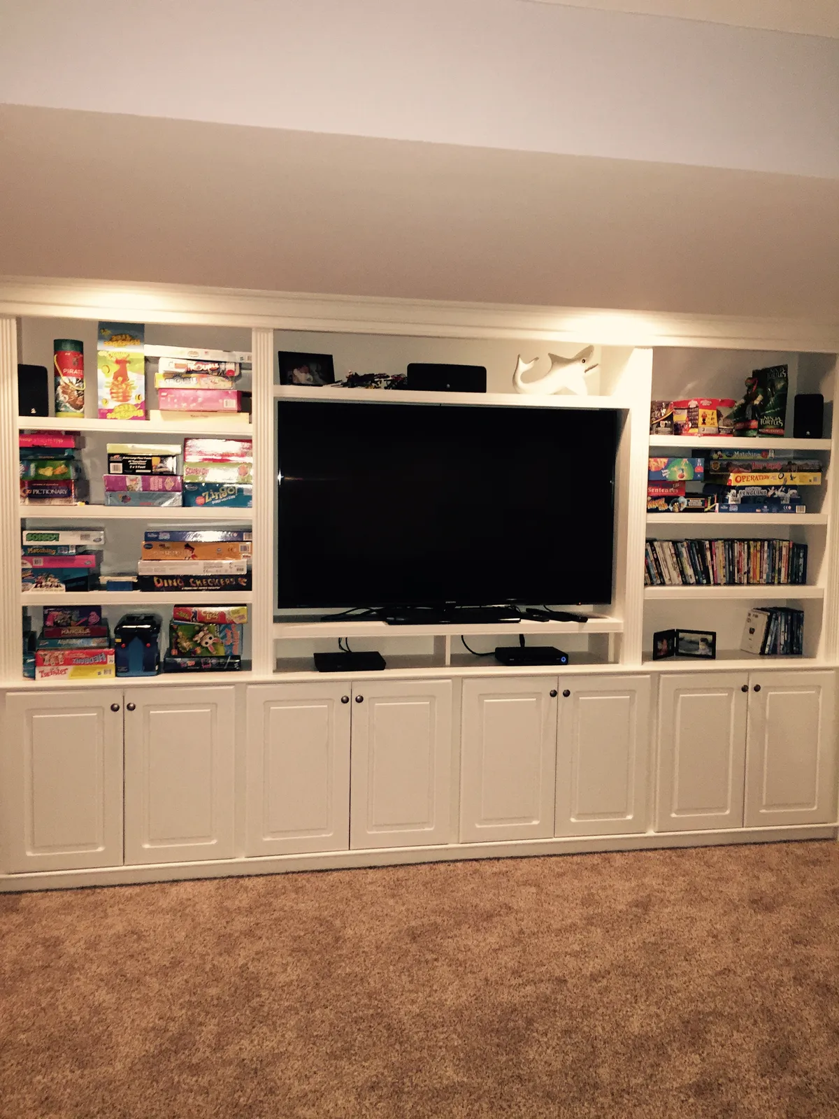 Finished basement media wall with built-in cabinets and shelving