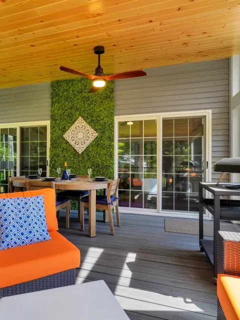 Bright porch with a ceiling fan, decorative green wall, and dining area.