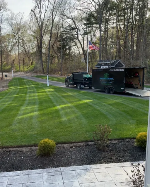Lawn care truck and trailer on a freshly mowed lawn. American flag in the background.