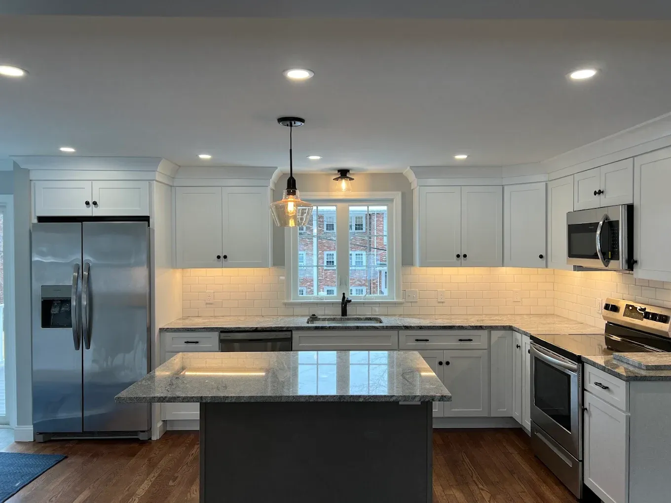 Kitchen with recessed ceiling lights, glass pendants over the sink and under-cabinet lighting installed by BW Electrical Contractors