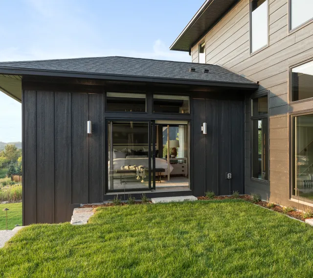 Black sliding patio door with vertical siding on modern home exterior