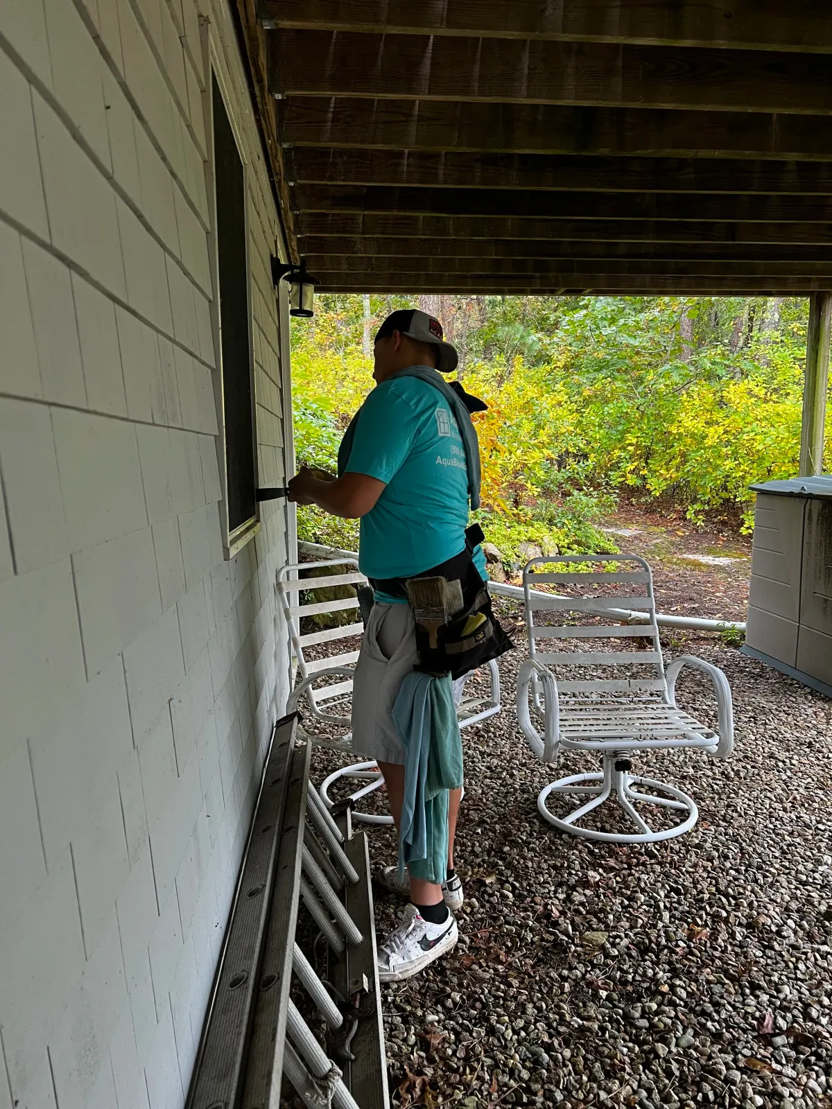 Person in teal shirt cleaning small window