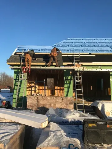 Construction workers installing roof on a new construction house.