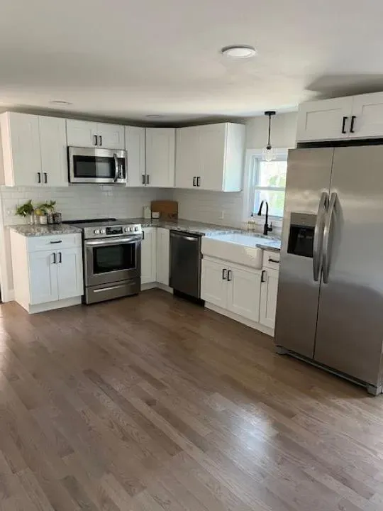 Dreamstate Renovations, LLC - Modern kitchen with white cabinetry, stainless steel appliances, and sleek countertops, showcasing expert kitchen renovation and remodeling with elegant finishes.