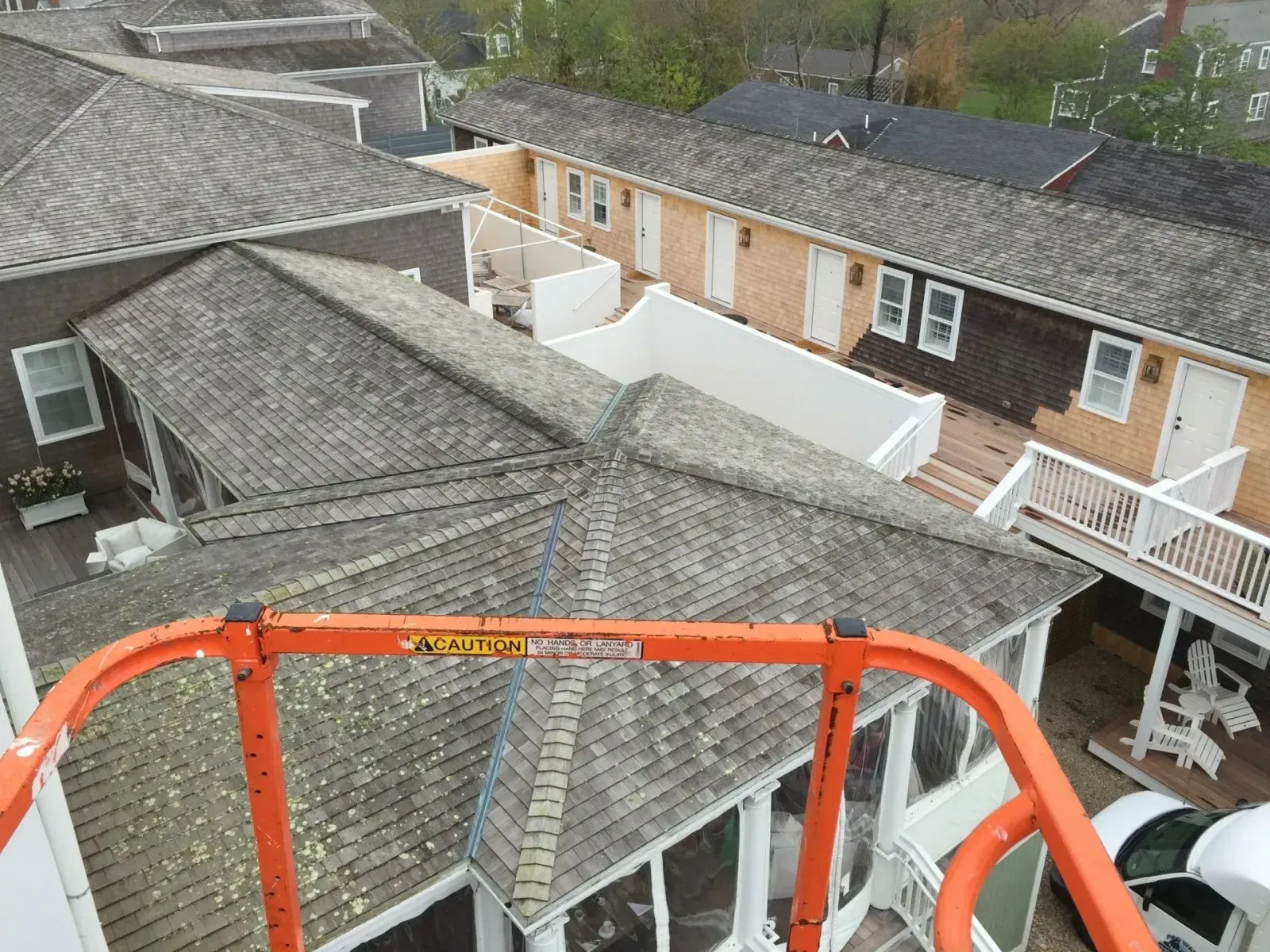View from an orange lift of multiple buildings with weathered roofs and white trim.