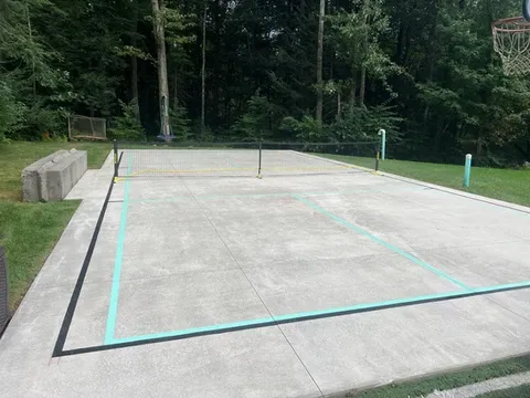 Outdoor concrete court with volleyball net and basketball hoop