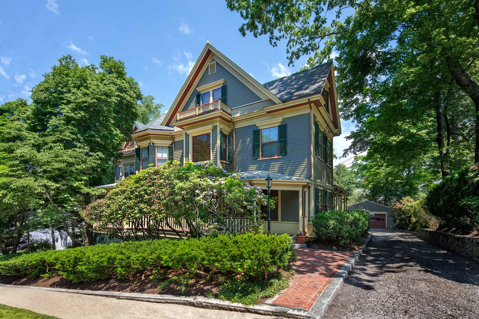 2-story blue home with red trim and long gravel driveway