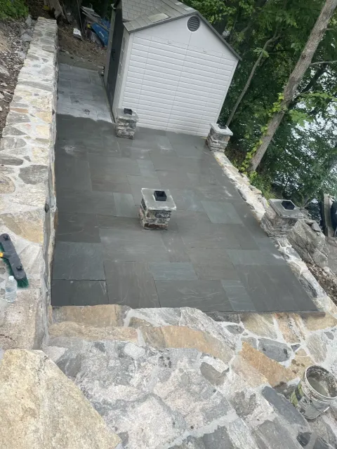 Bluestone patio with a built in fire pit and surrounding stone walls