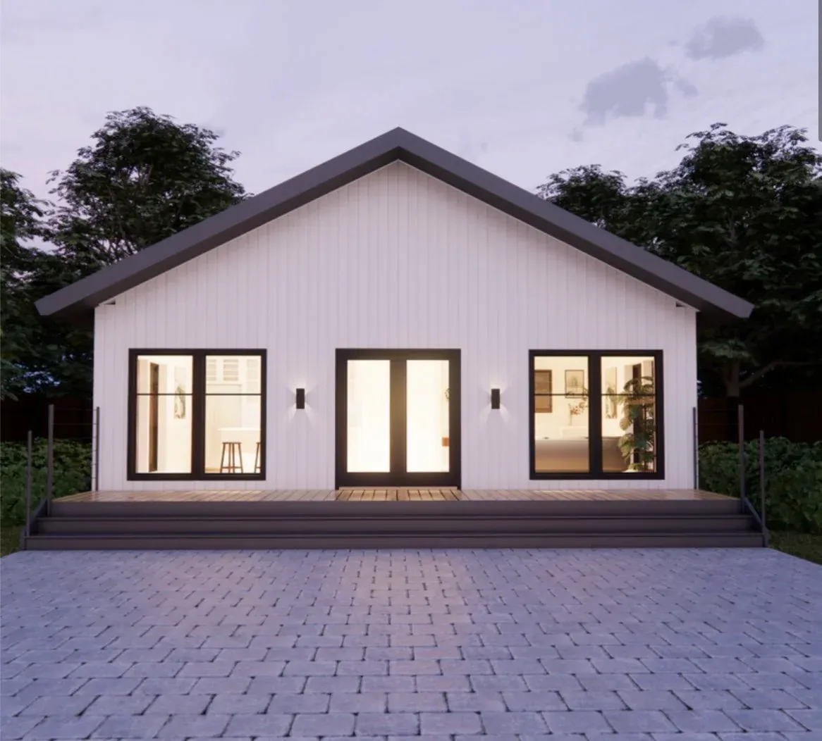Modern white house with large glass doors and windows, a raised wooden porch, and a paved front yard, surrounded by trees.