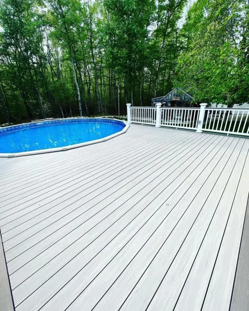 A large wooden deck with a swimming pool in the background