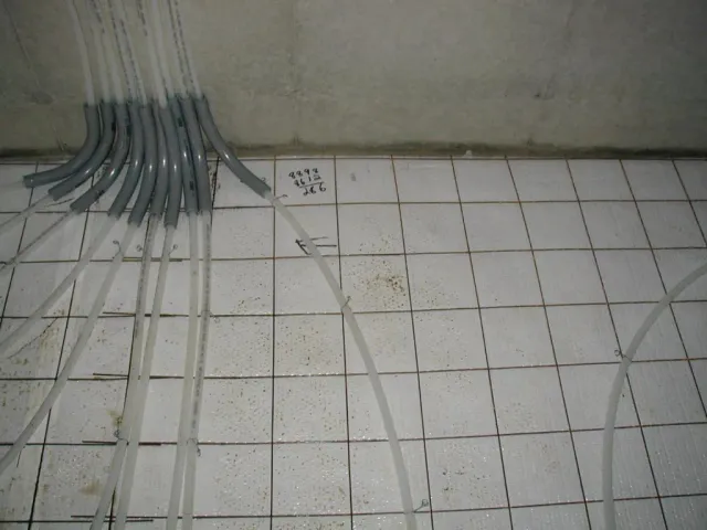 A bunch of wires are laying on a tiled floor