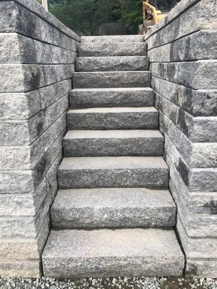 Stone steps between gray retaining walls leading upward outdoors