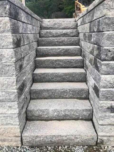 Stone steps between gray retaining walls leading upward outdoors