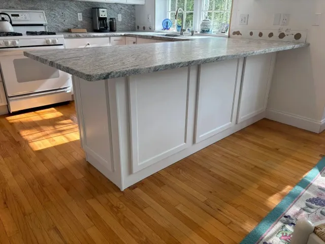 White kitchen island with granite countertop. Hardwood floors.