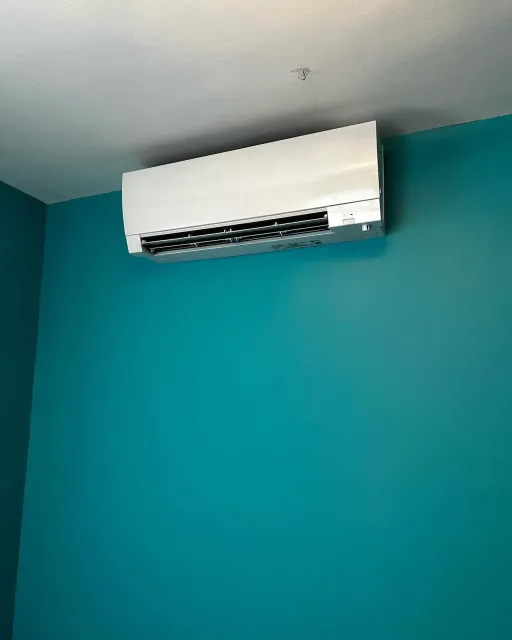 a white air conditioner is hanging from the ceiling in a room with blue walls