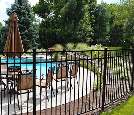 Backyard patio with fenced swimming pool, table and chairs, and a closed umbrella