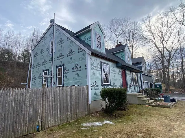 A house with a fence in front of it is being remodeled.