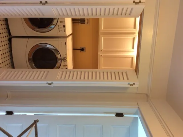 Finished laundry area with louvered doors and upper cabinets