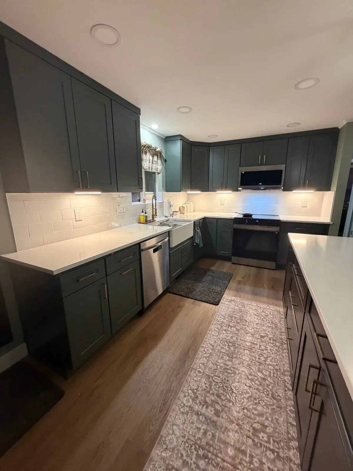 Kitchen remodel with dark green shaker cabinets, white subway tile, farmhouse sink, and hardwood floors