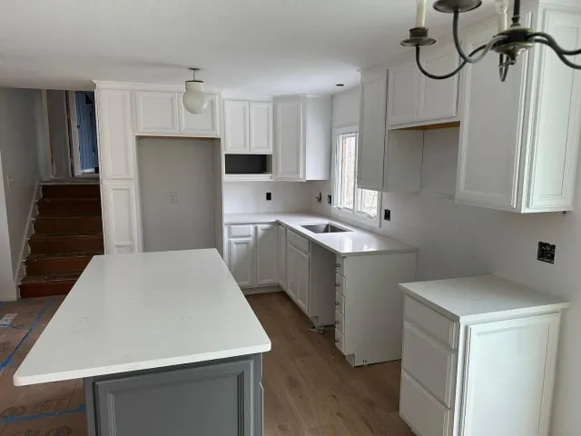 A kitchen with white cabinets and a large island in the middle.