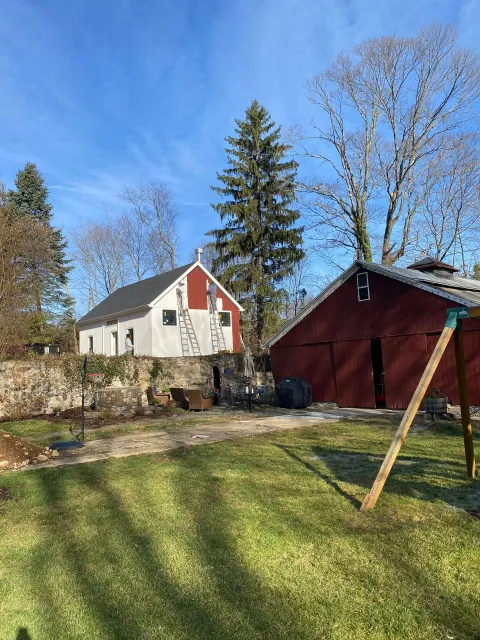 There is a red barn and a white barn in the background.