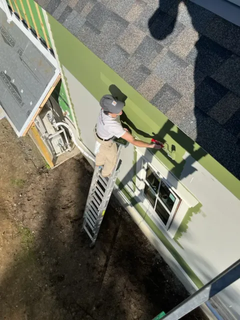 Paintable painter rolling fresh paint on Vermont home siding