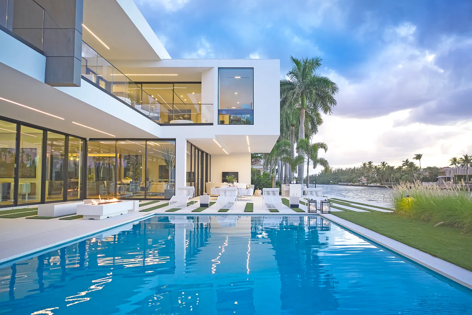 Modern waterfront pool terrace with lawn inlays and fire feature