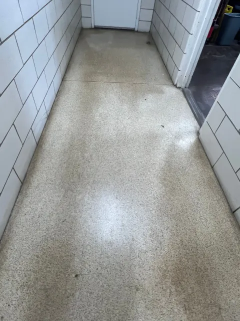 A hallway with a brick wall and a white floor.