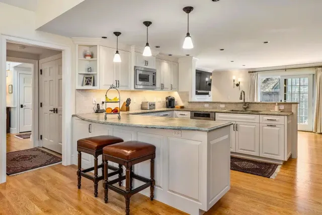 Open kitchen with island seating, pendant lights, and granite counters.