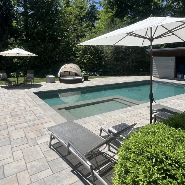 A large swimming pool surrounded by chairs and umbrellas