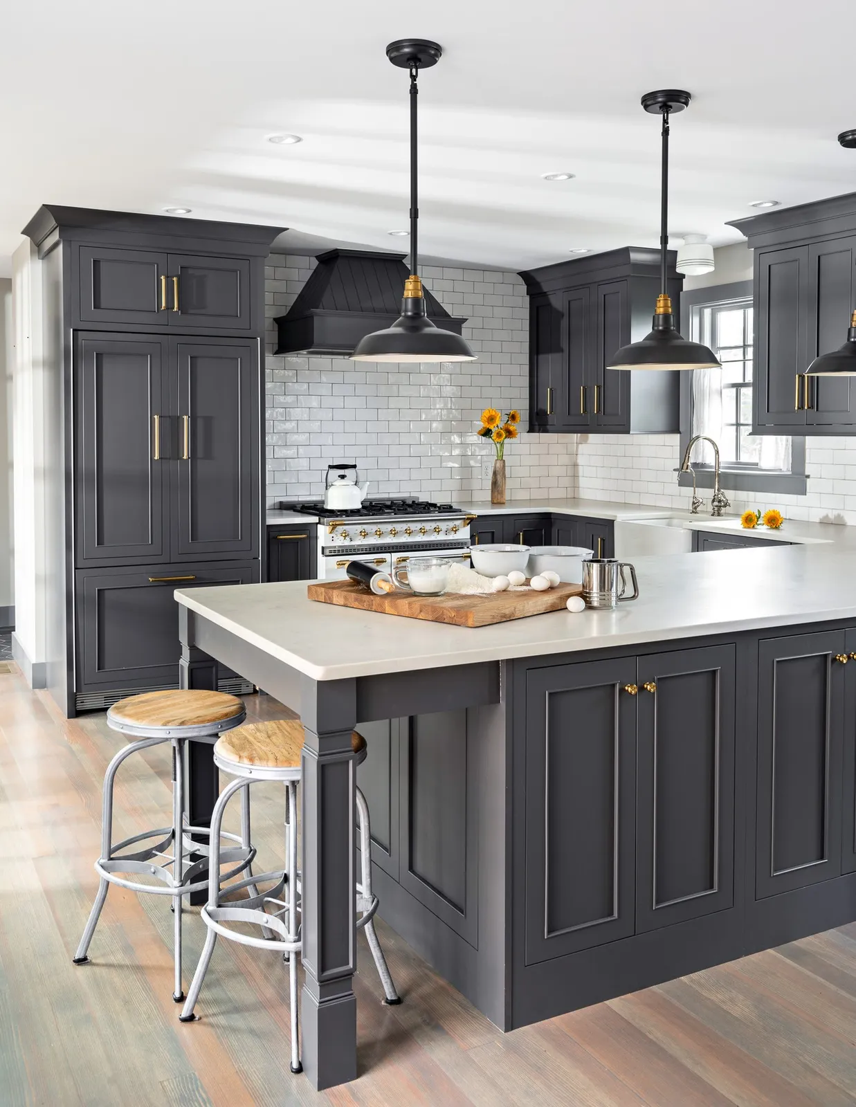 In this Provincetown home renovation, the kitchen finds its character through contrast, craftsmanship, and a carefully layered palette. Deep charcoal cabinetry creates a dramatic foundation, while warm brass hardware, softly reflective tile, and a classic white range bring light and dimension to the room.

The millwork was designed to feel architectural rather than simply functional. Floor-to-ceiling cabinetry maximizes storage, glass-front doors introduce moments of display, and integrated wine storage adds a tailored detail. The custom range hood and substantial crown molding complete the composition, giving the renovated kitchen a sense of permanence within the home.

Viewed through the dining room’s glass doors, the kitchen feels both refined and welcoming—a space designed for everyday Cape Cod living and gathering in Provincetown.

#Provincetown #CapeCodInteriors #CustomCabinetry #ArchitecturalMillwork #KitchenRenovation #InteriorDetails #CapeCodHomes #CapeAssociates
